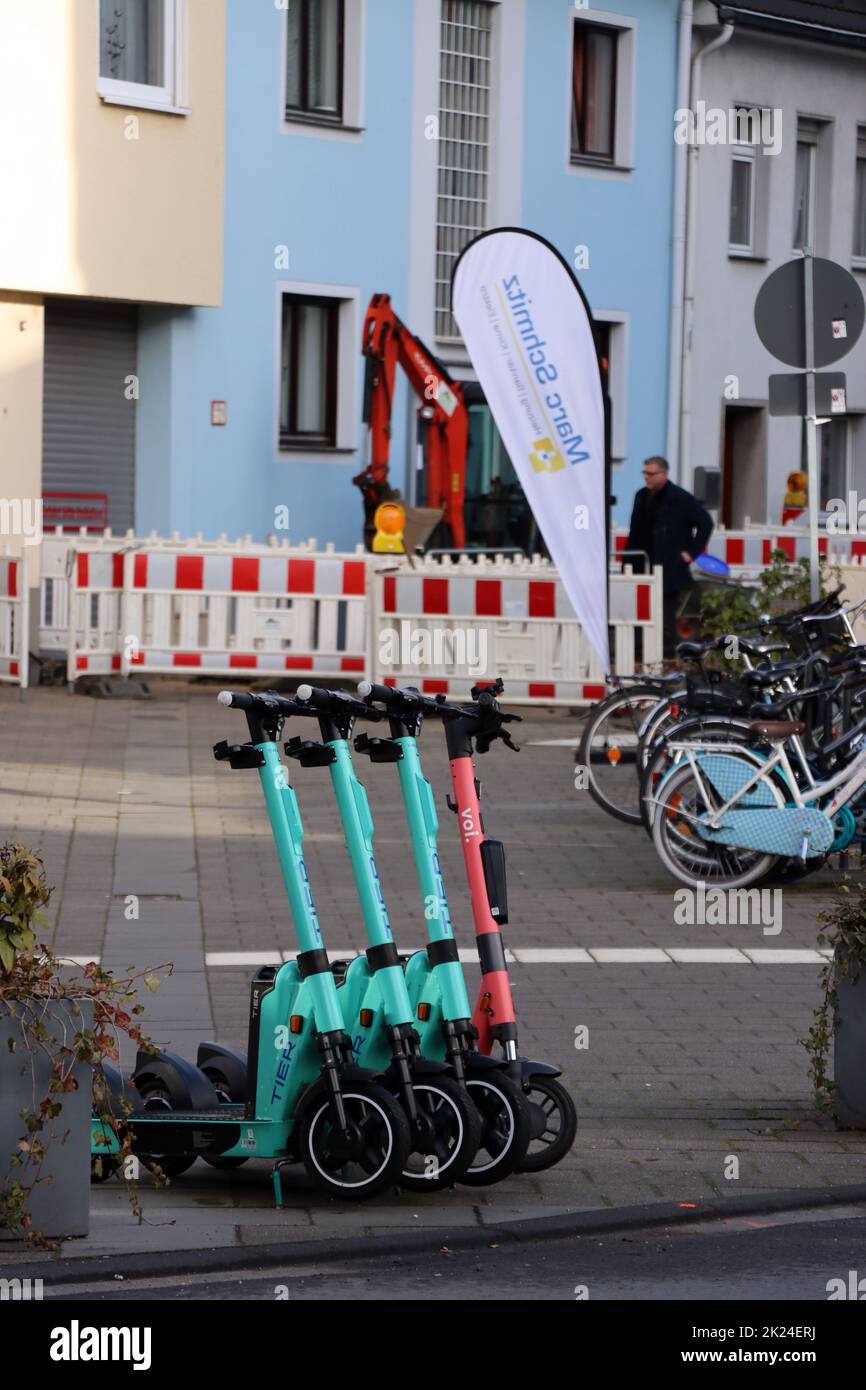 vier e-Scooter veschiedener Anbieter stehen aufgereiht am Strassenrand, Nordrhein-Westfalen, Deutschland, Köln-Rodenkirchen Stock Photo