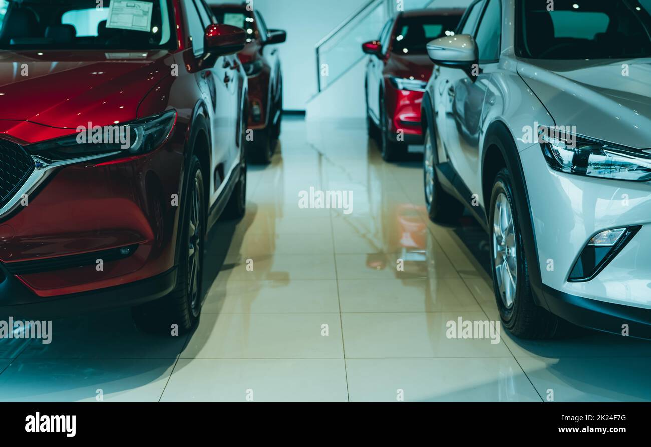 Front view red SUV and white car parked in luxury showroom. Car