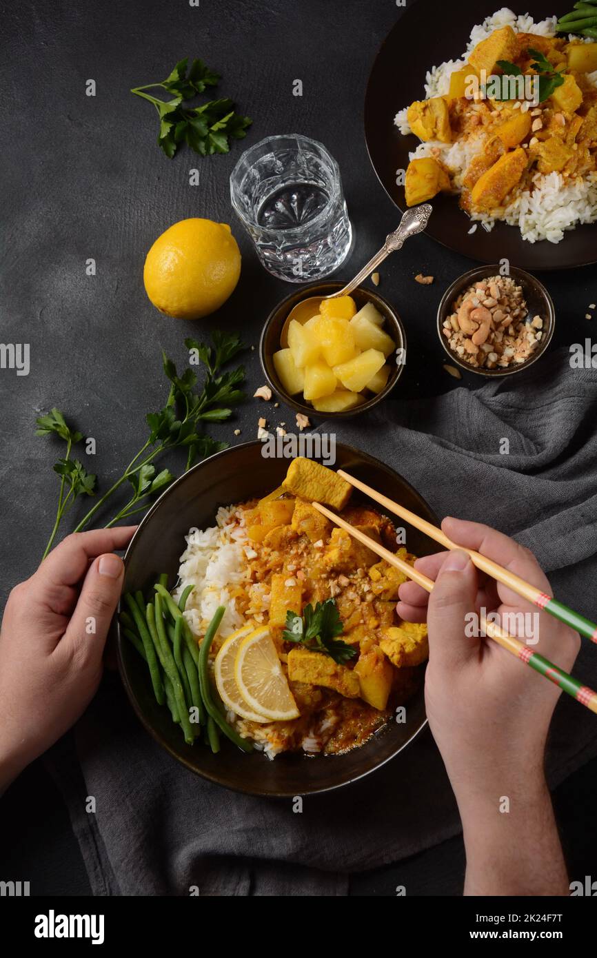 A Chicken Massaman Curry in black bowl at dark background. Massaman Curry is Thai Indian best dish with chicken meat, potato, onion and many spices is Stock Photo
