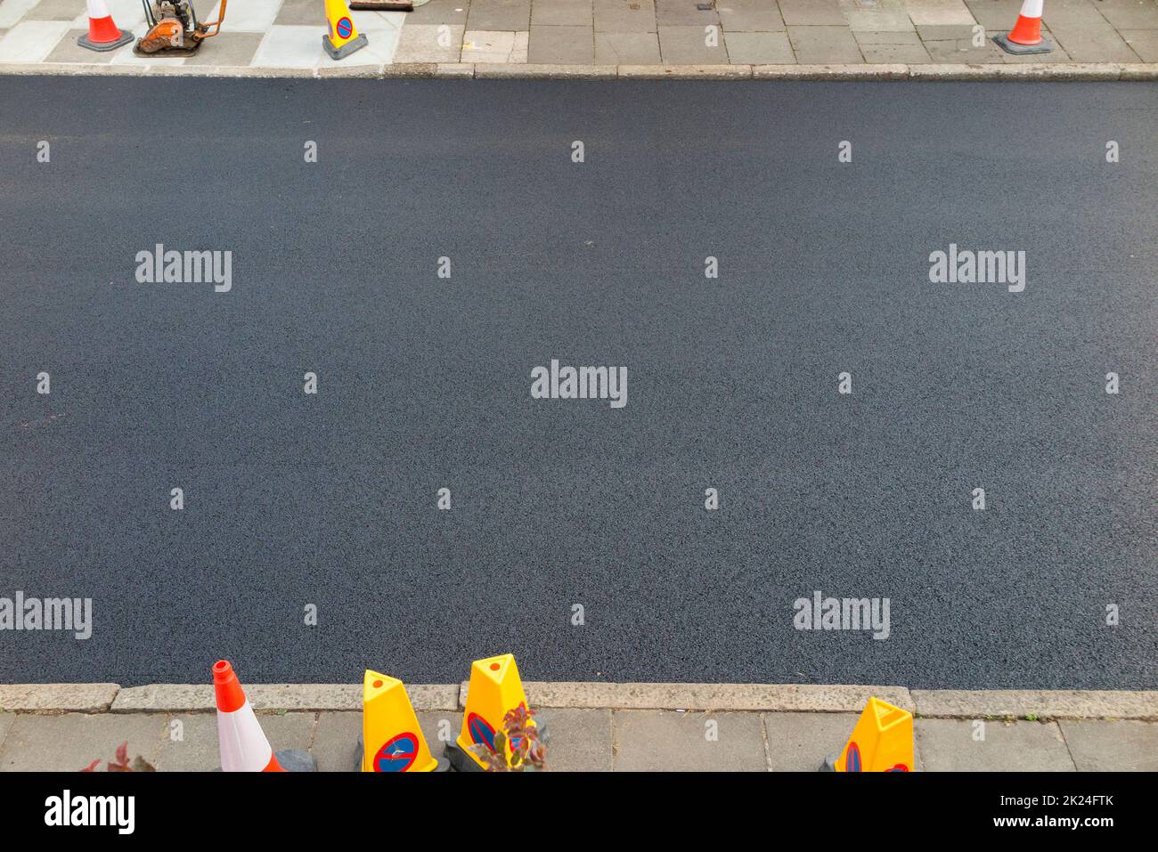 A beautiful fresh newly laid layer of hot fresh and smooth tarmac on the road just after a roller smoothing and rolling machine has rolled the tarmacadam. The new surface has been laid while resurfacing a residential Street in Twickenham, Greater London, UK. (132) Stock Photo
