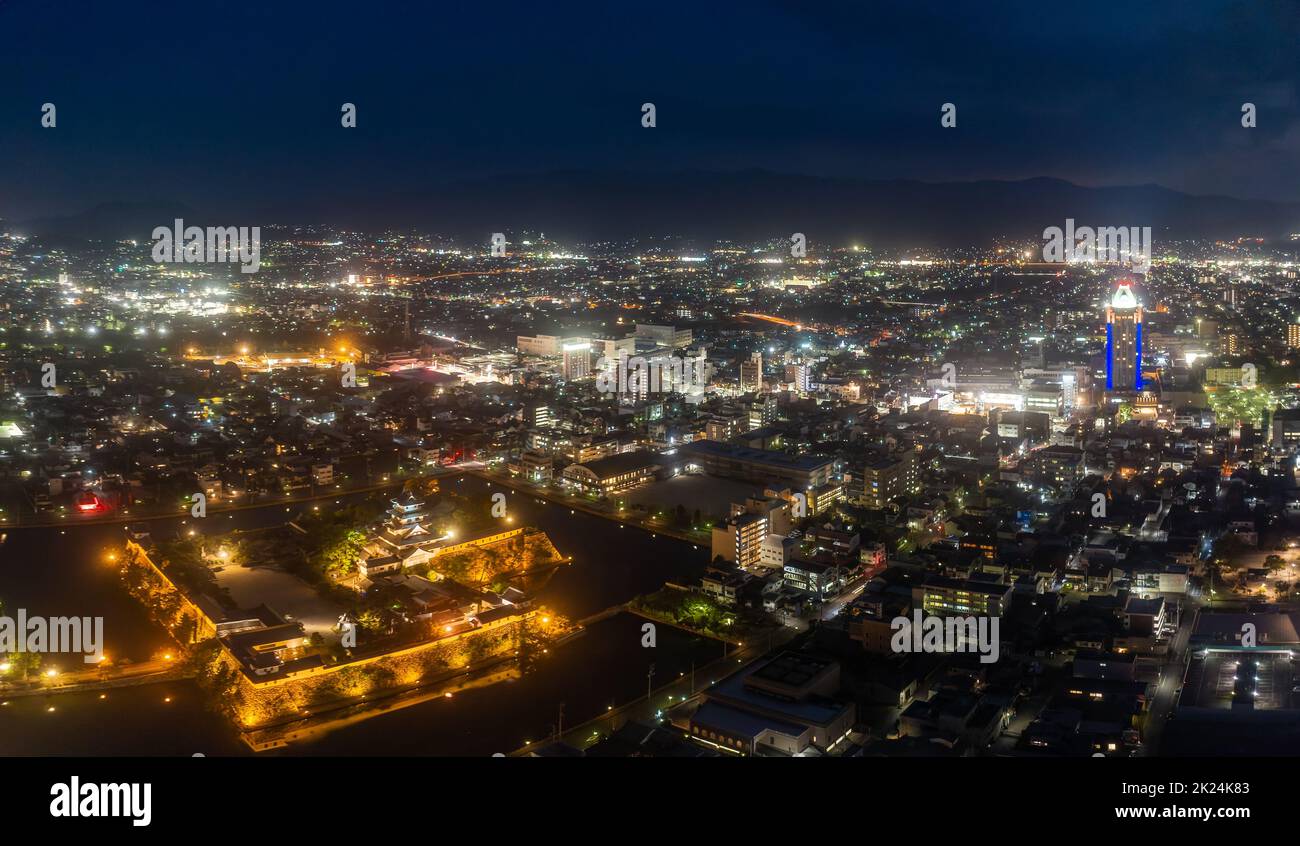Ancient Japanese castle and city center lights in early evening Stock Photo