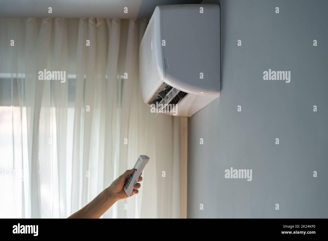 Owner tries to turn on air conditioner to allow stream of warm air to make apartment hotter Stock Photo