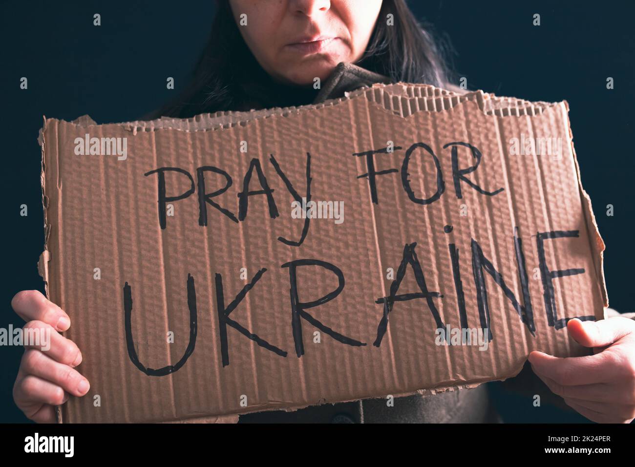 Woman holds a banner with anti-war message. Protest against the Russian intervention to Ukraine, activism and human rights movement. Concept of standi Stock Photo