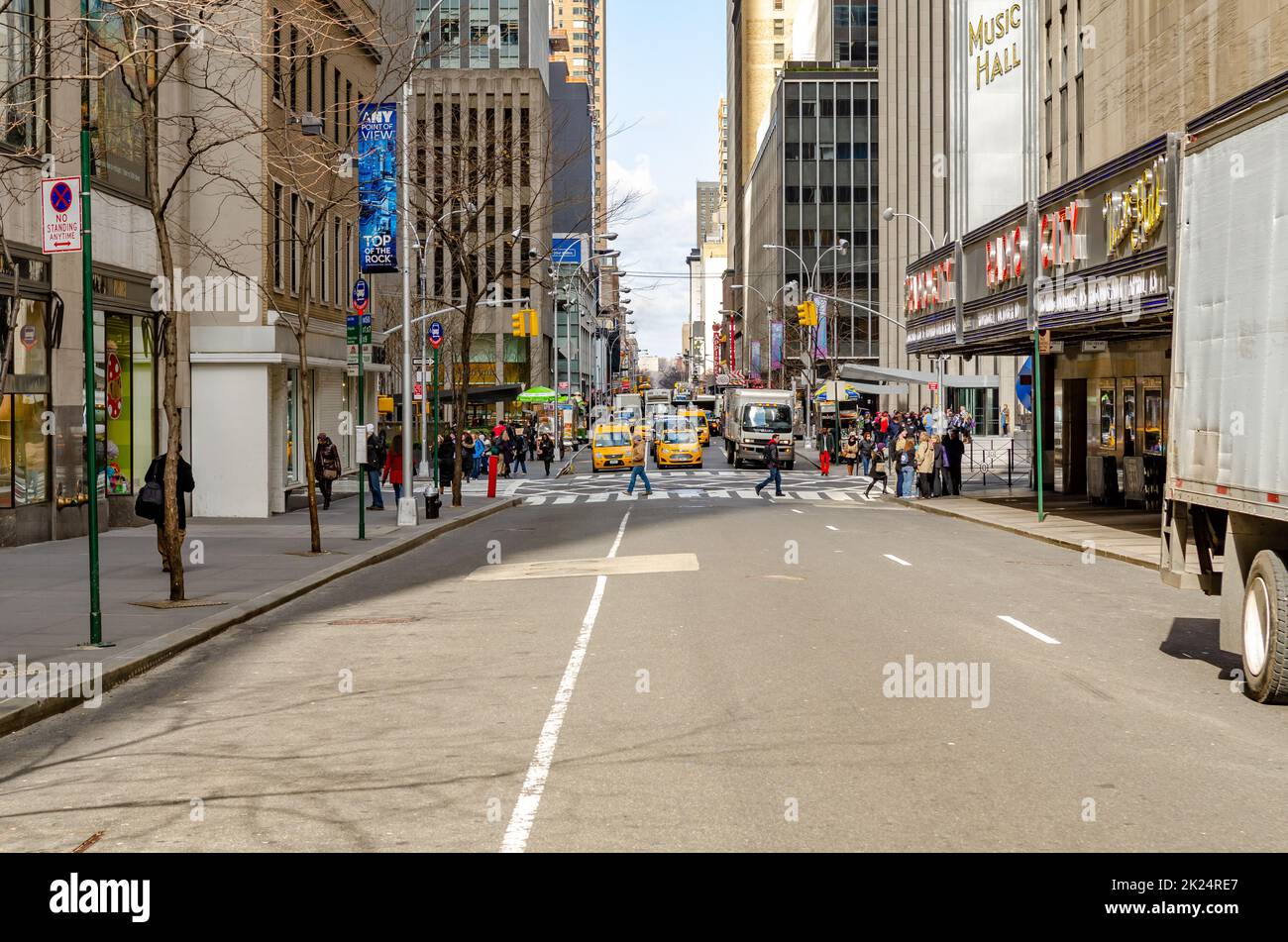 New York City Street next to Radio City Music Hall with traffic, yellow Taxi Cabs and cars, on the horizon behind two crosswalks during daytime, horiz Stock Photo