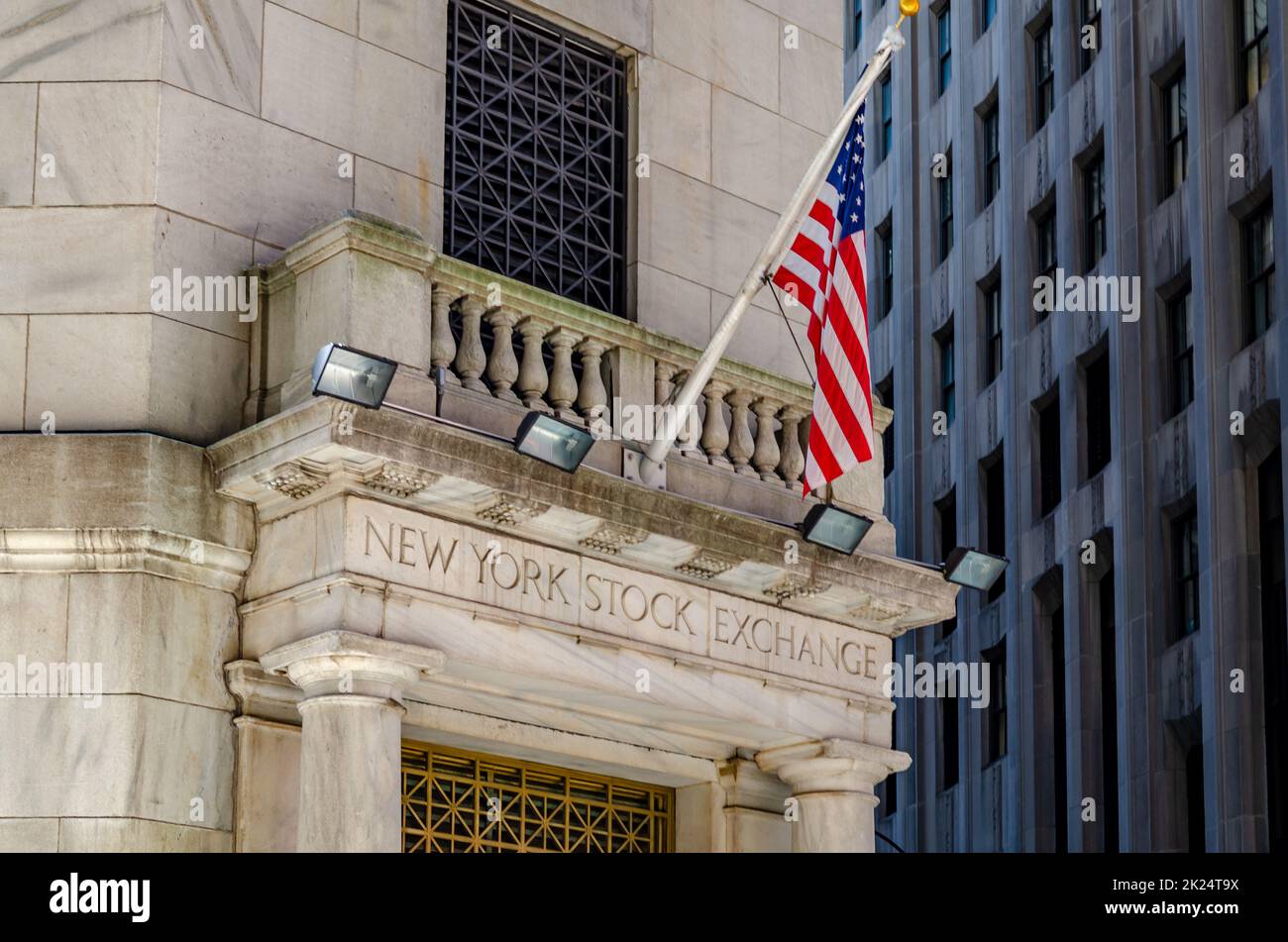 New York Stock Building Exchange golden colored Building Entrance, close-up with American Flag above during winter, vertical Stock Photo