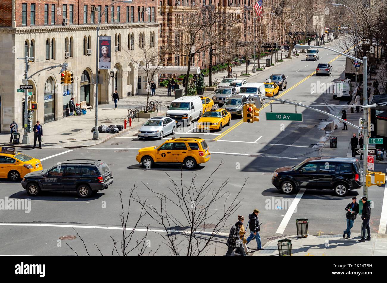 Crossroads at Chelsea, New York City with lots of yellow taxi cabs and cars passing by during sunny winter day, Brown Building facades in the backgrou Stock Photo
