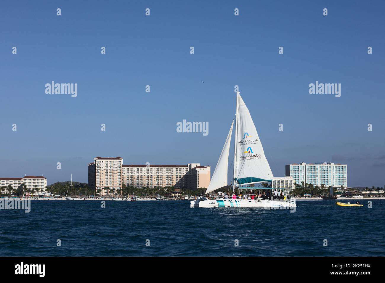 PALM BEACH, ARUBA - OCTOBER 17, 2021: Catamaran tour boat sailing along Palm Beach in front of the Marriott and Radisson Blu hotels on the Caribbean i Stock Photo