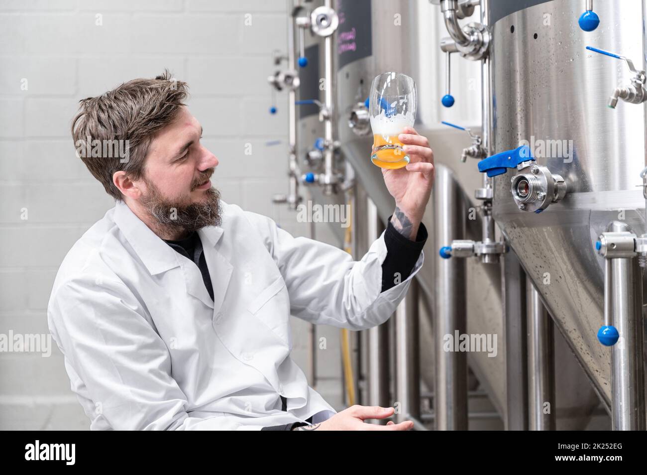 Brewer wearing white coat controlling process of beer fermentation