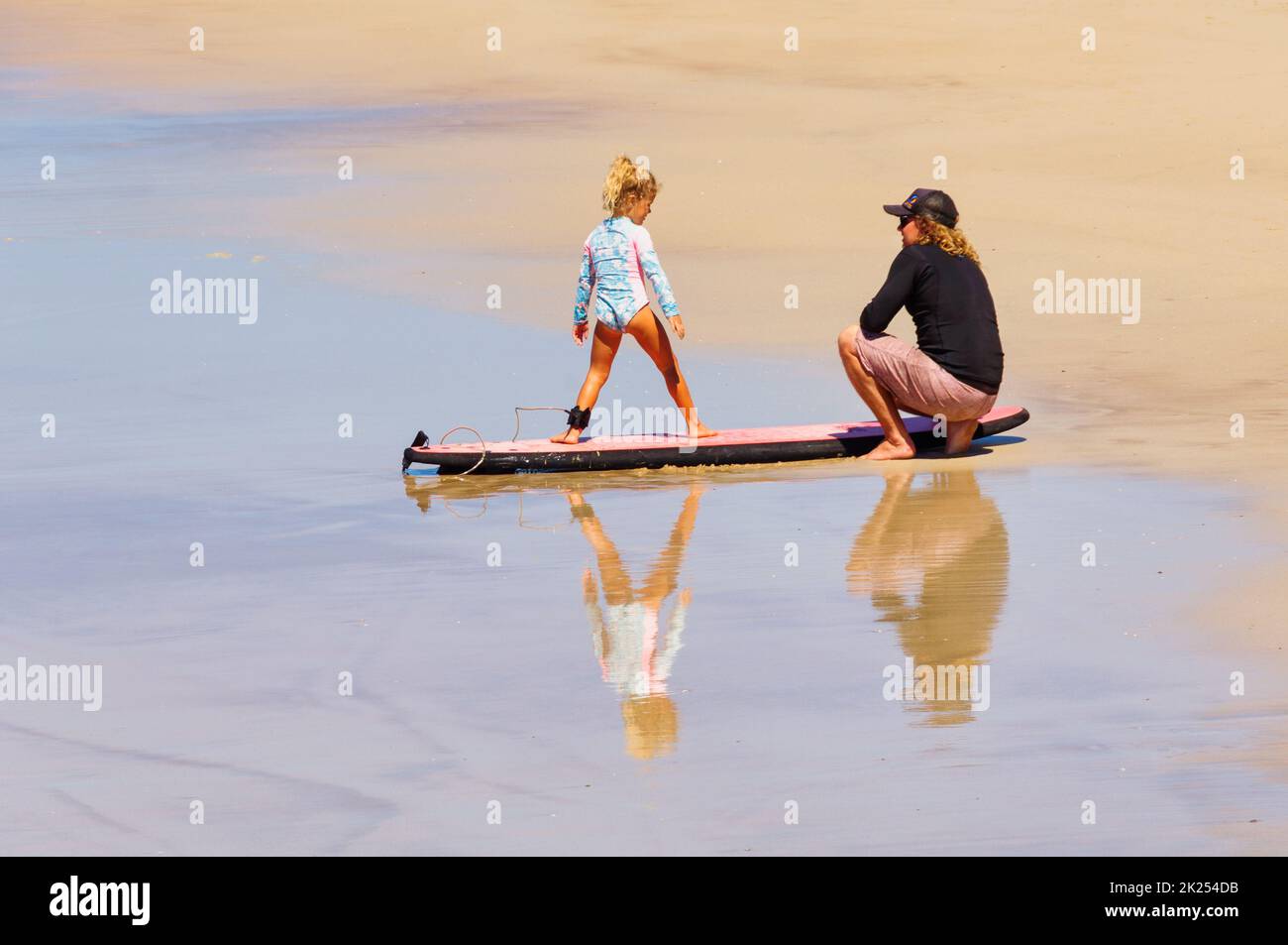 A father is teaching her young daughter to surf - Coffs Harbour, NSW, Australia Stock Photo