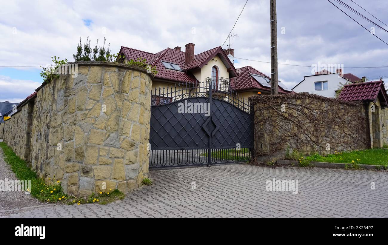 Wroclaw, Poland - April 17, 2022: Residential neighborhood of Wroclaw. Small simple two storey detached house with pitched roof, stone fence. Stock Photo