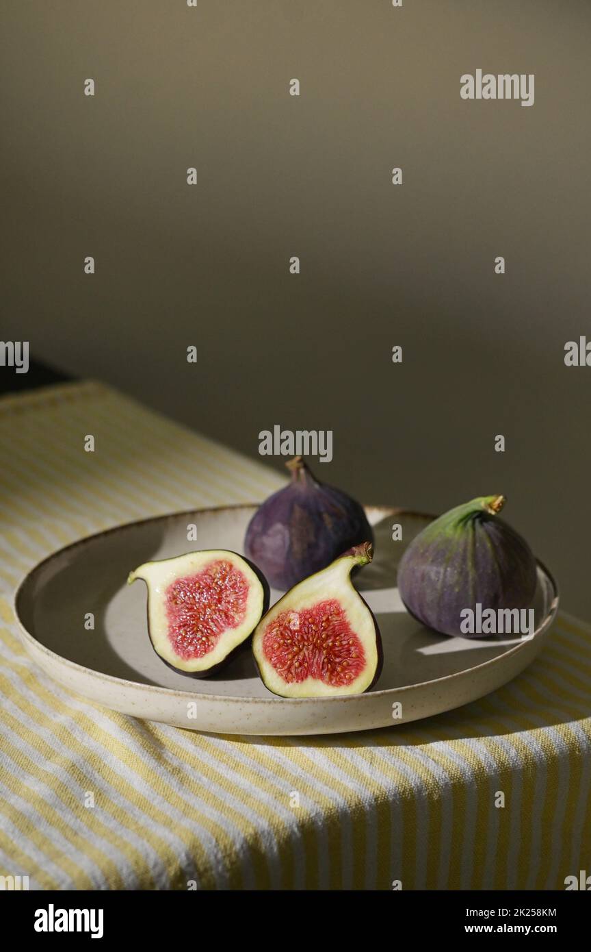 Figs fruits placed on a small plate on a table with a tablecloth and sunshine Stock Photo