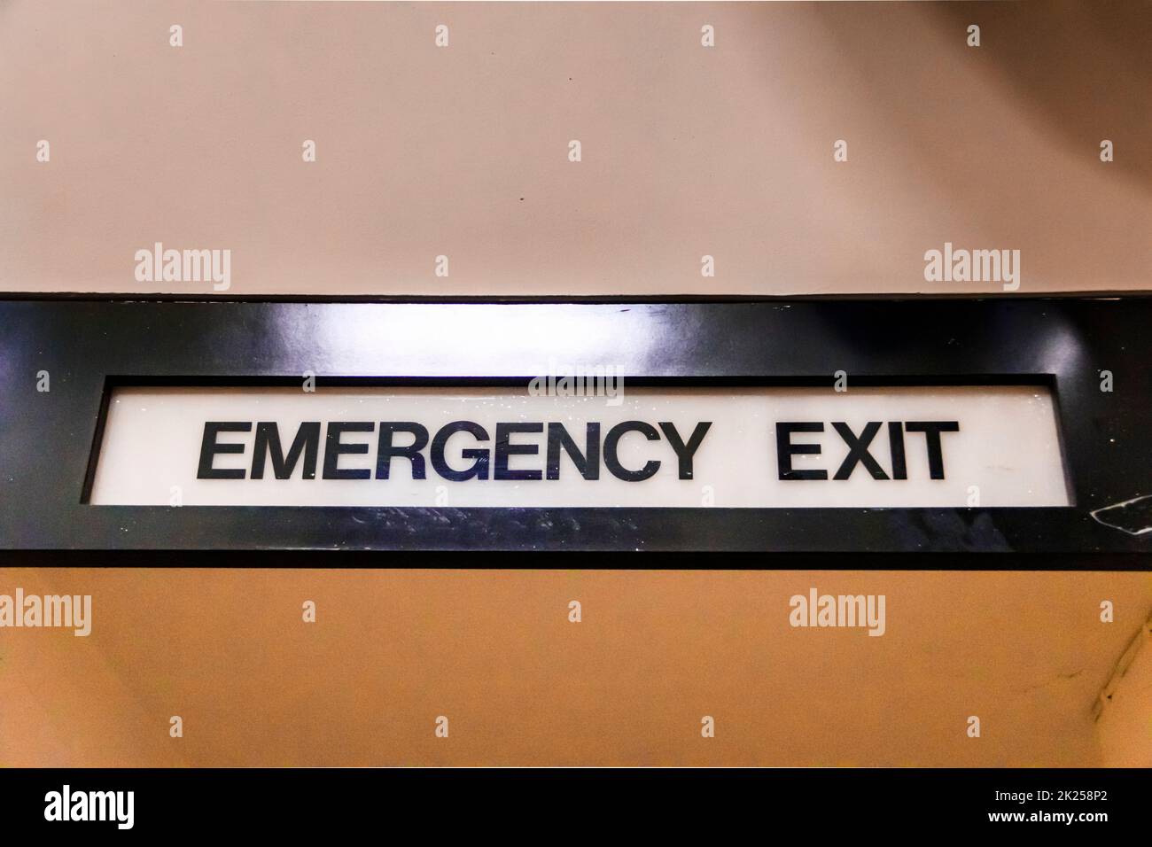 An emergency exit sign above a door in a community centre Stock Photo