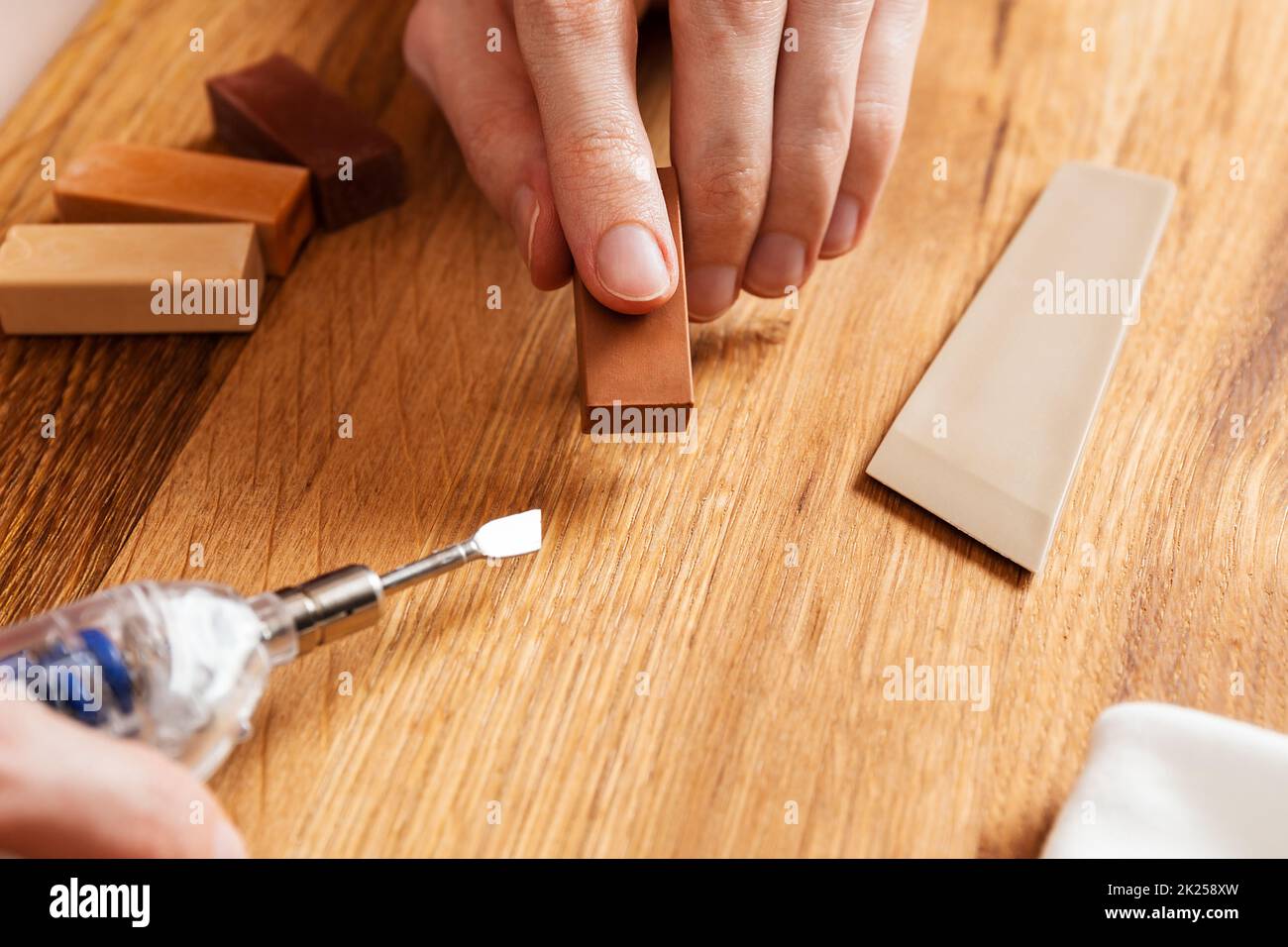 Man heating hard wax for repair cracks, scratches, dents in the wooden