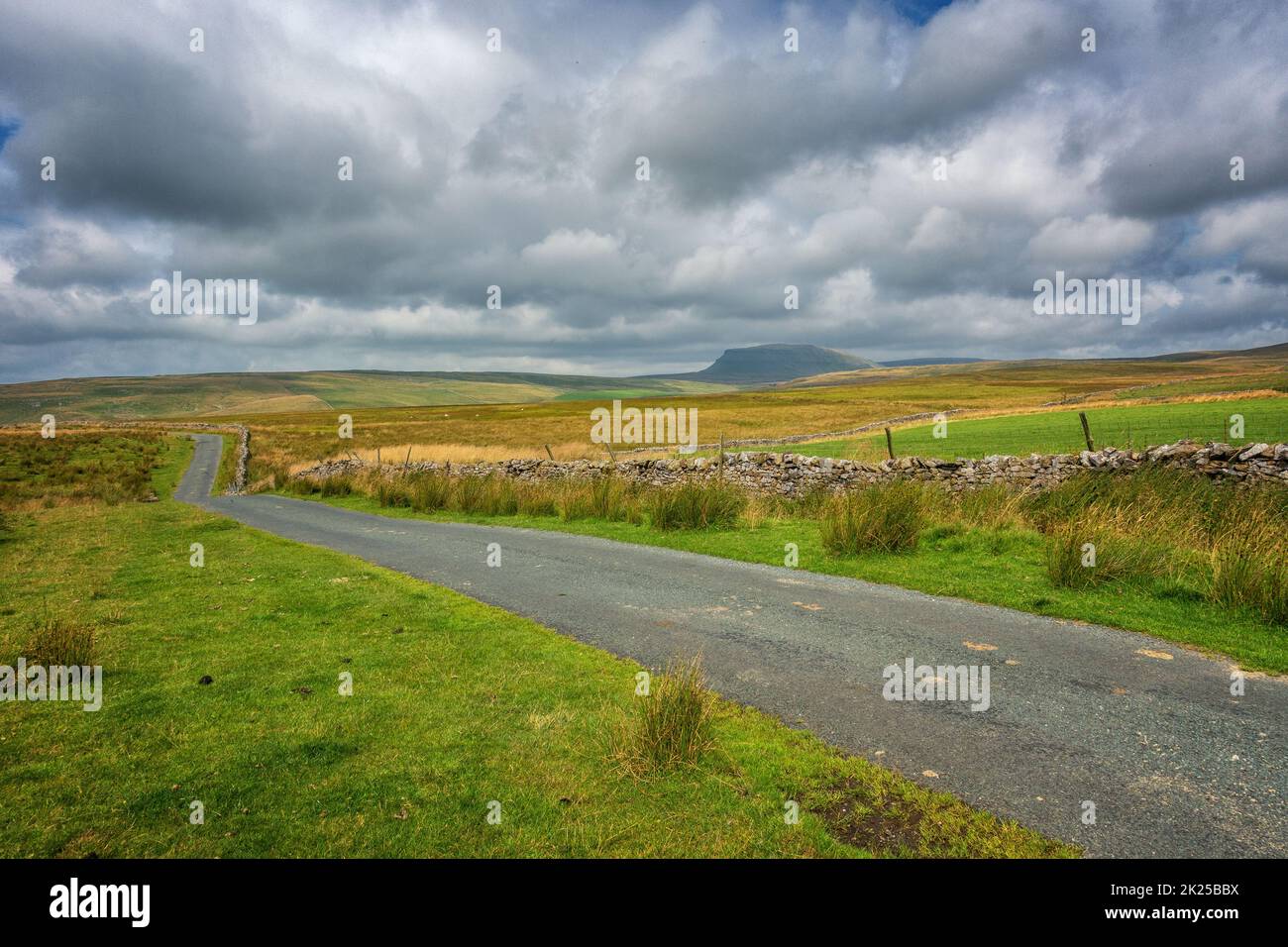 Country lane over Malham Moor looking towards Pen-y-ghent mountain, Yorkshire Dales National Park, North Yorkshire, England, UK Stock Photo