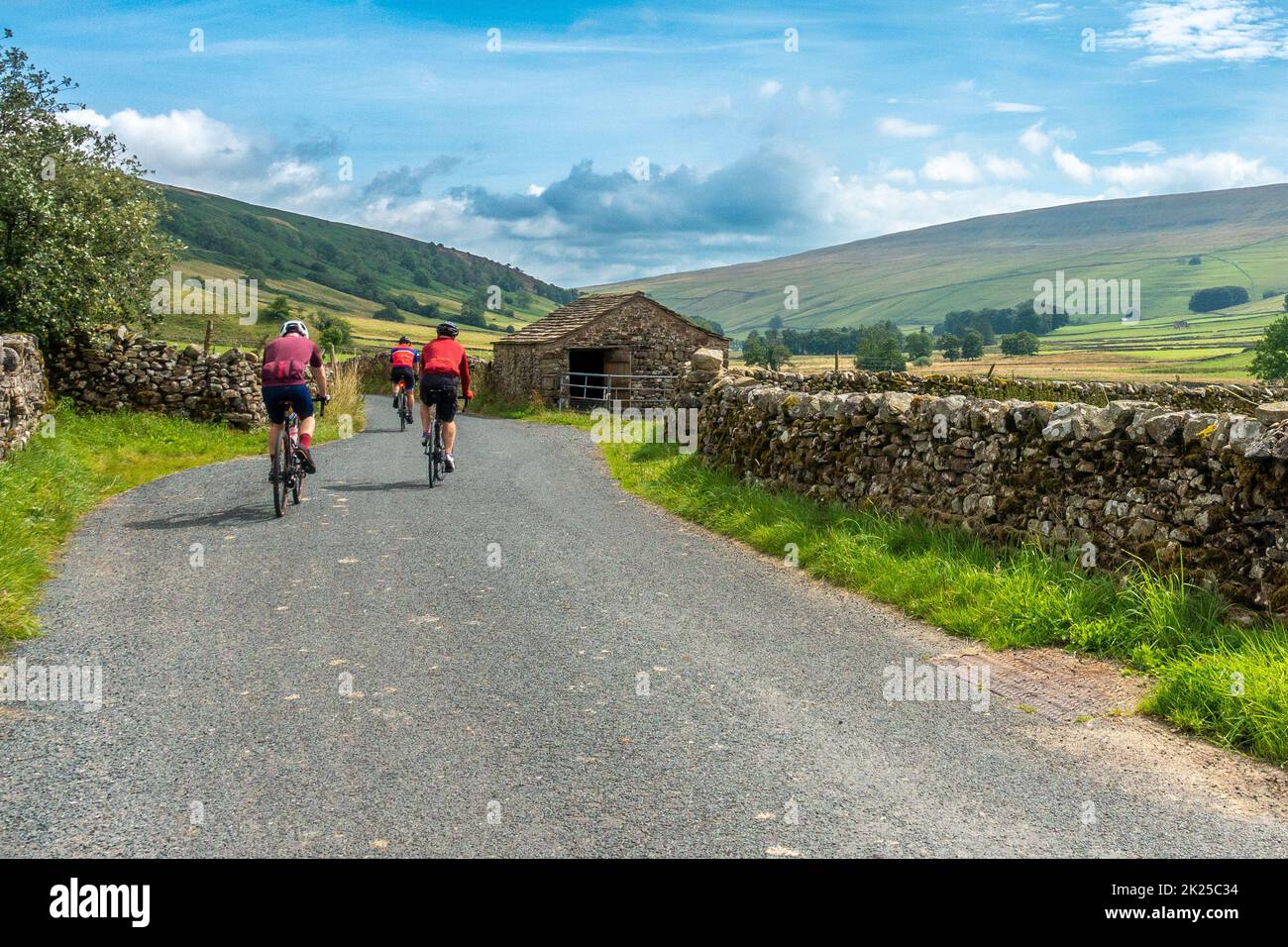 Three male cyclists socialising on bikes on a country lane near Halton Gill with views of Littondale, Yorkshire Dales National Park, North Yorkshire, Stock Photo