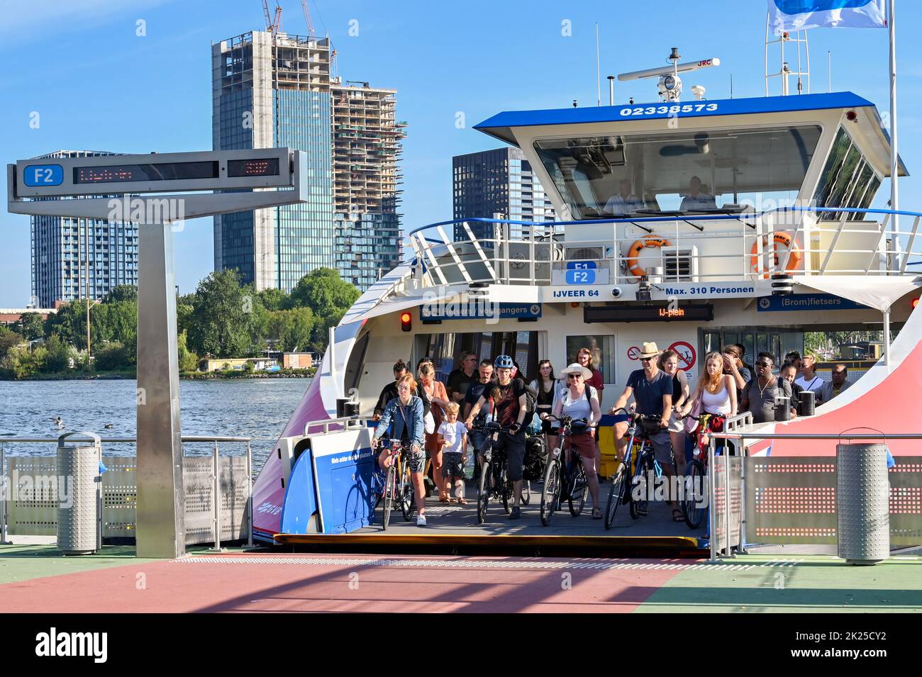 Amsterdam, Netherlands - August 2022: People on bicycles about to ride off a shuttle ferry service on the waterfront in Amsterdam Stock Photo