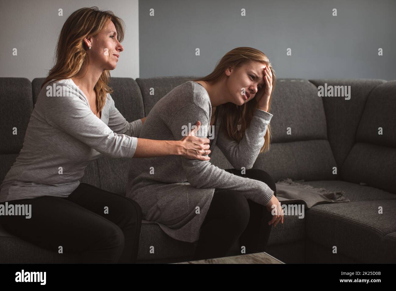 Depressed teen suffering from anxiety being taken care of by her caring mother Stock Photo