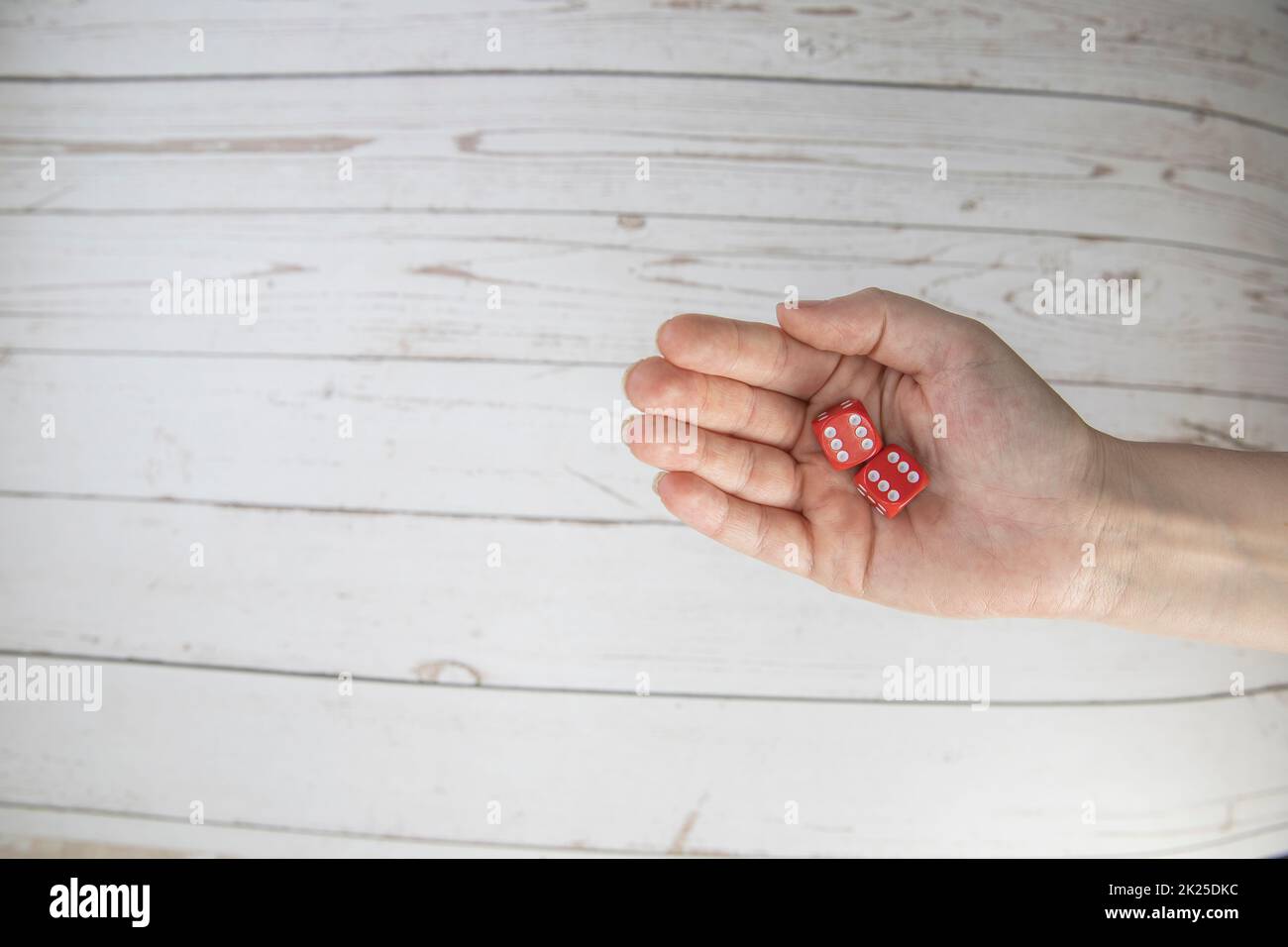 Female hand holds red gaming dice on white background. Double six Concept with copy space for games, game board, role playing game, risk, chance, good luck or gambling. Toned image top view. Close-up. Stock Photo