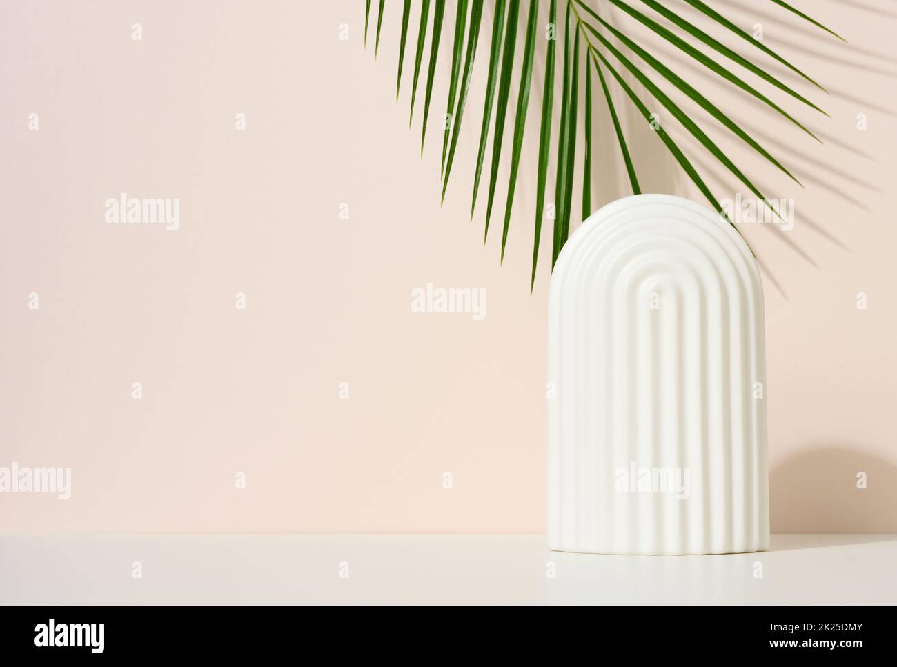 podium with white arches to showcase cosmetics, products and other merchandise. Green palm leaf Stock Photo