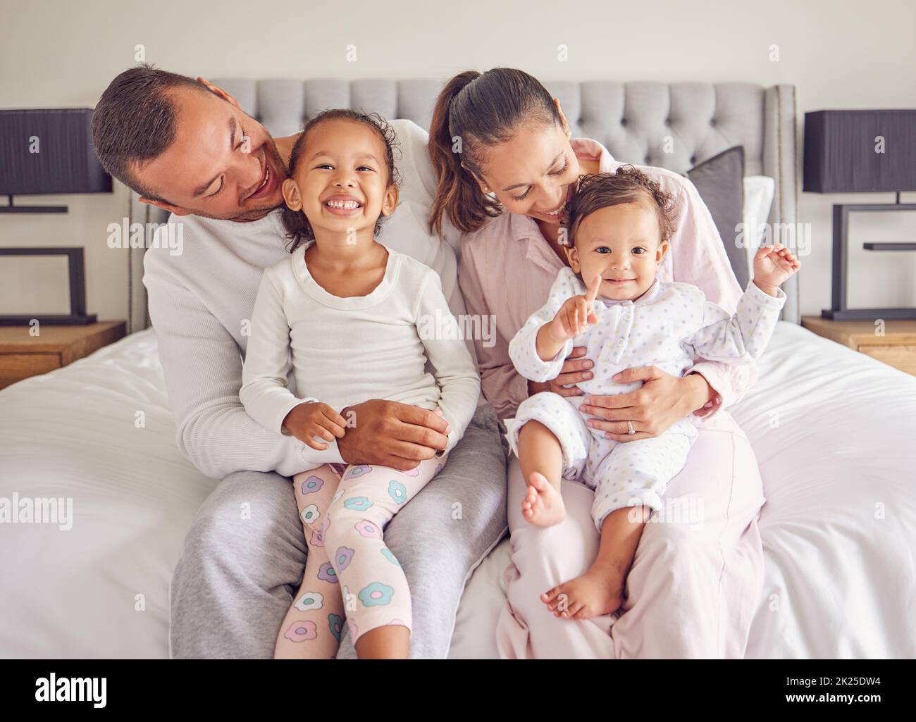 Family, bonding and bed time with children and parents smile and rest together, loving and caring in bedroom. Play, sleep and routine by young man and Stock Photo