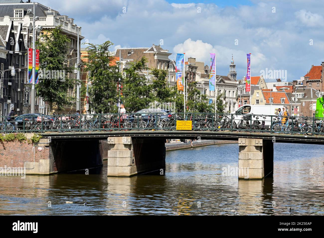 Amsterdam, Netherlands - August 2022: Bridge over one of the city's canals with bicycles parked by commuters Stock Photo