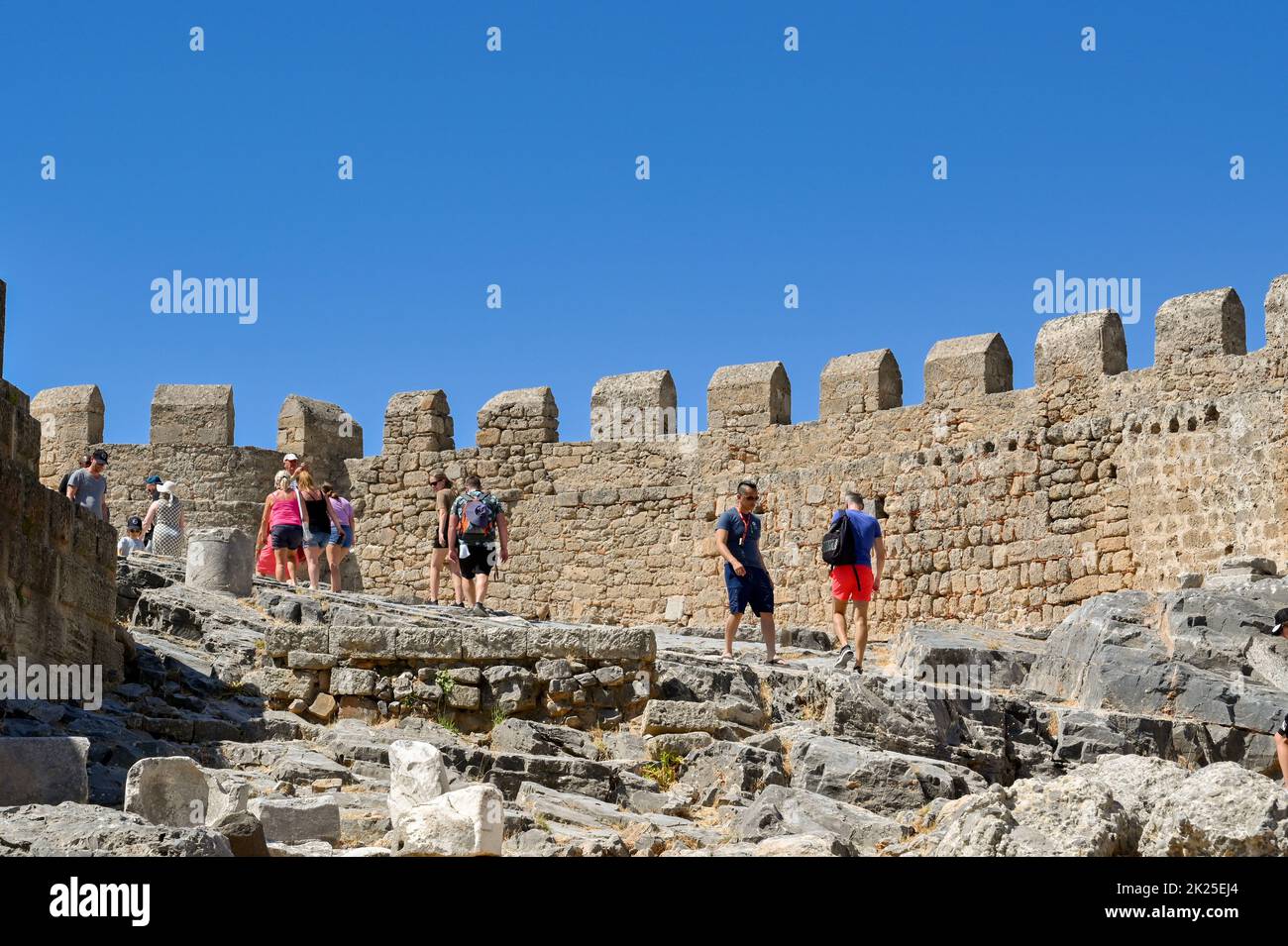 Lindos, Rhodes, Greece - June 2022: People walking over the ruins of the ancient acropolis in Lindos Stock Photo