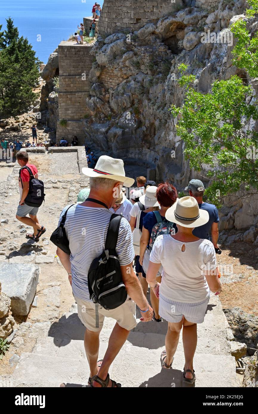 Lindos, Rhodes, Greece - June 2022: People walking down steps after visiting the ruins of the ancient acropolis in Lindos Stock Photo