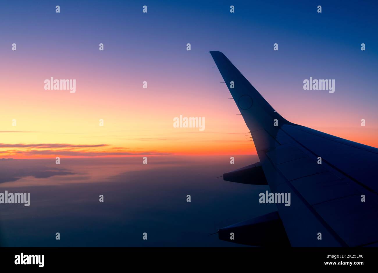Wing of plane with sunrise skyline. Airplane flying in the sky. Scenic view from airplane window. Commercial airline flight. Plane wing above clouds. International flight. Travel abroad after covid-19 Stock Photo