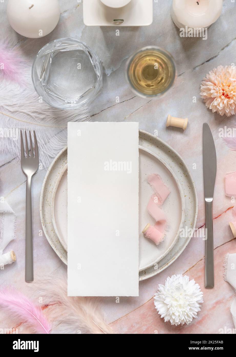 Wedding Table place with a card near pink flowers, feathers and silk