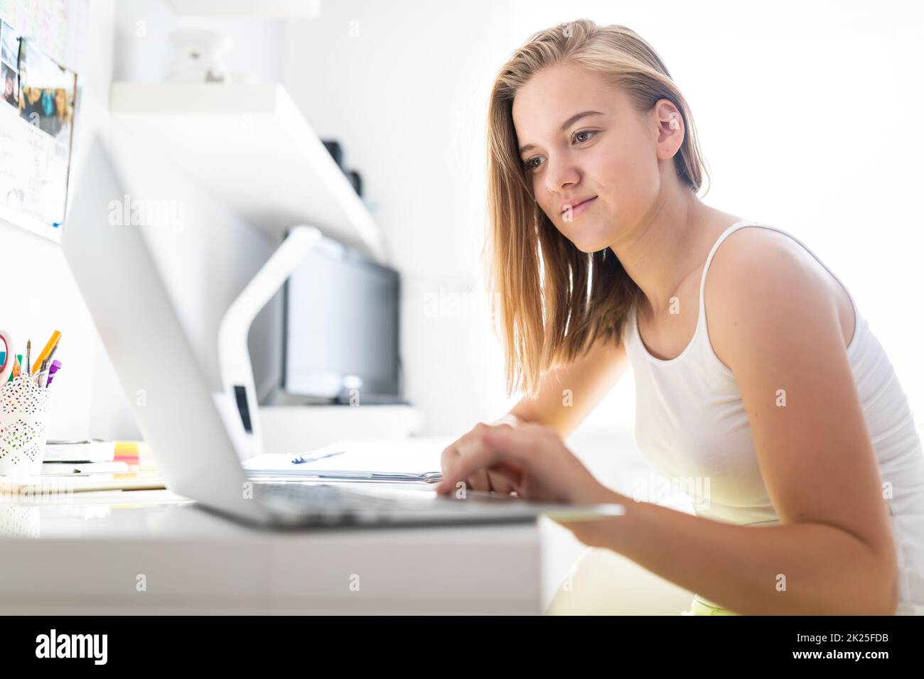 Teenage girl homeschooled due to COVID pandemics, following online classes Stock Photo