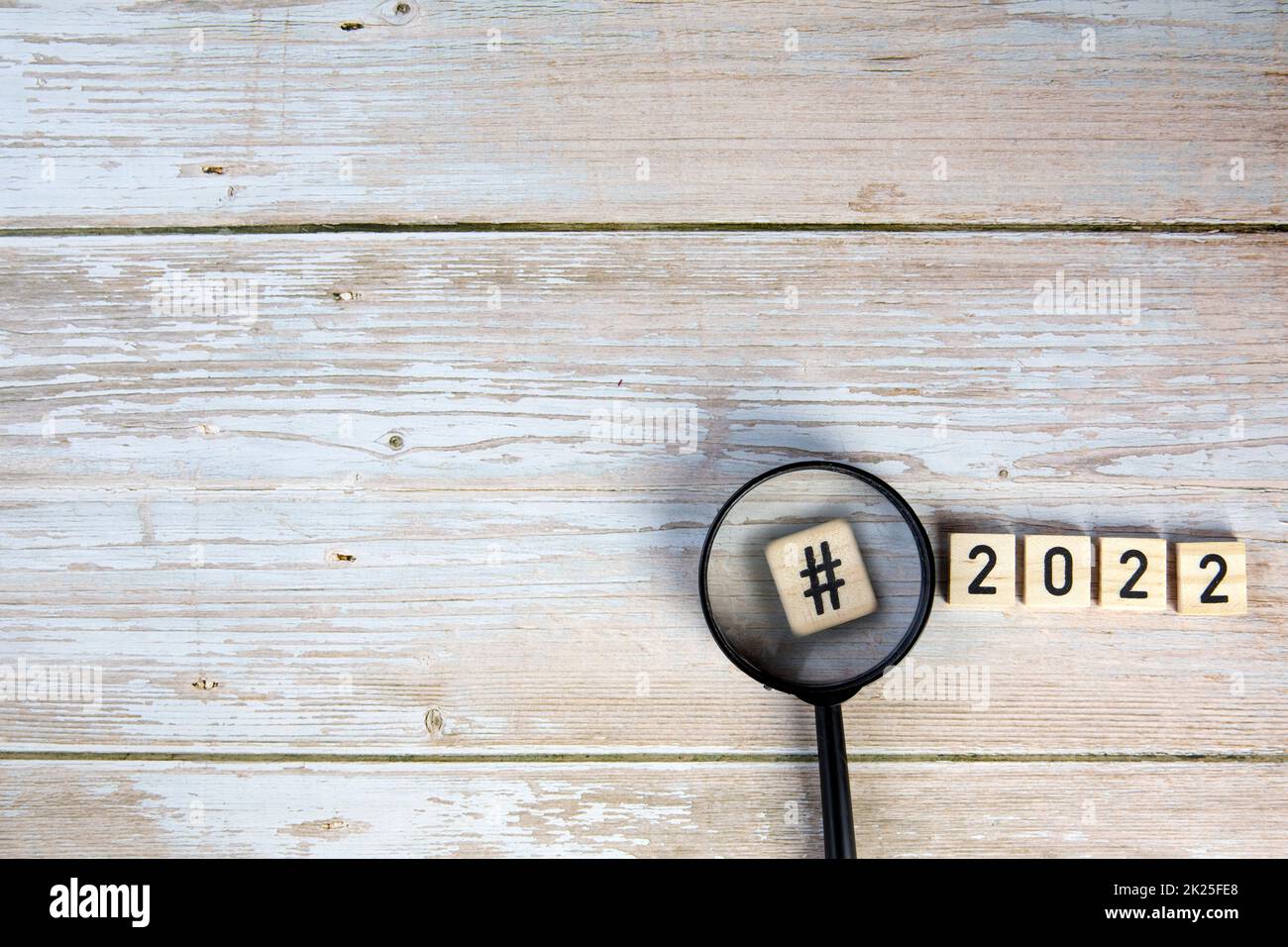 2022 with Hashtag and magnifying glass Concept on wooden background top view, copy space, New Year Stock Photo