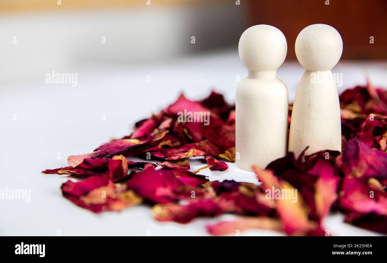 Real love, lover, couple concept. Two wooden figures with red rose petals on white background, standing together isolated on white background. copy space Stock Photo