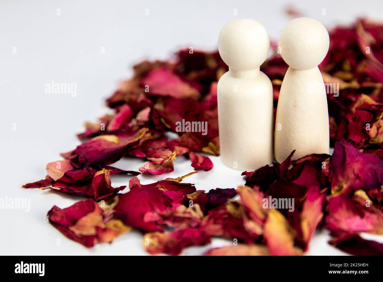 Real love, lover, couple concept. Two wooden figures with red rose petals on white background, standing together isolated on white background. copy space Stock Photo