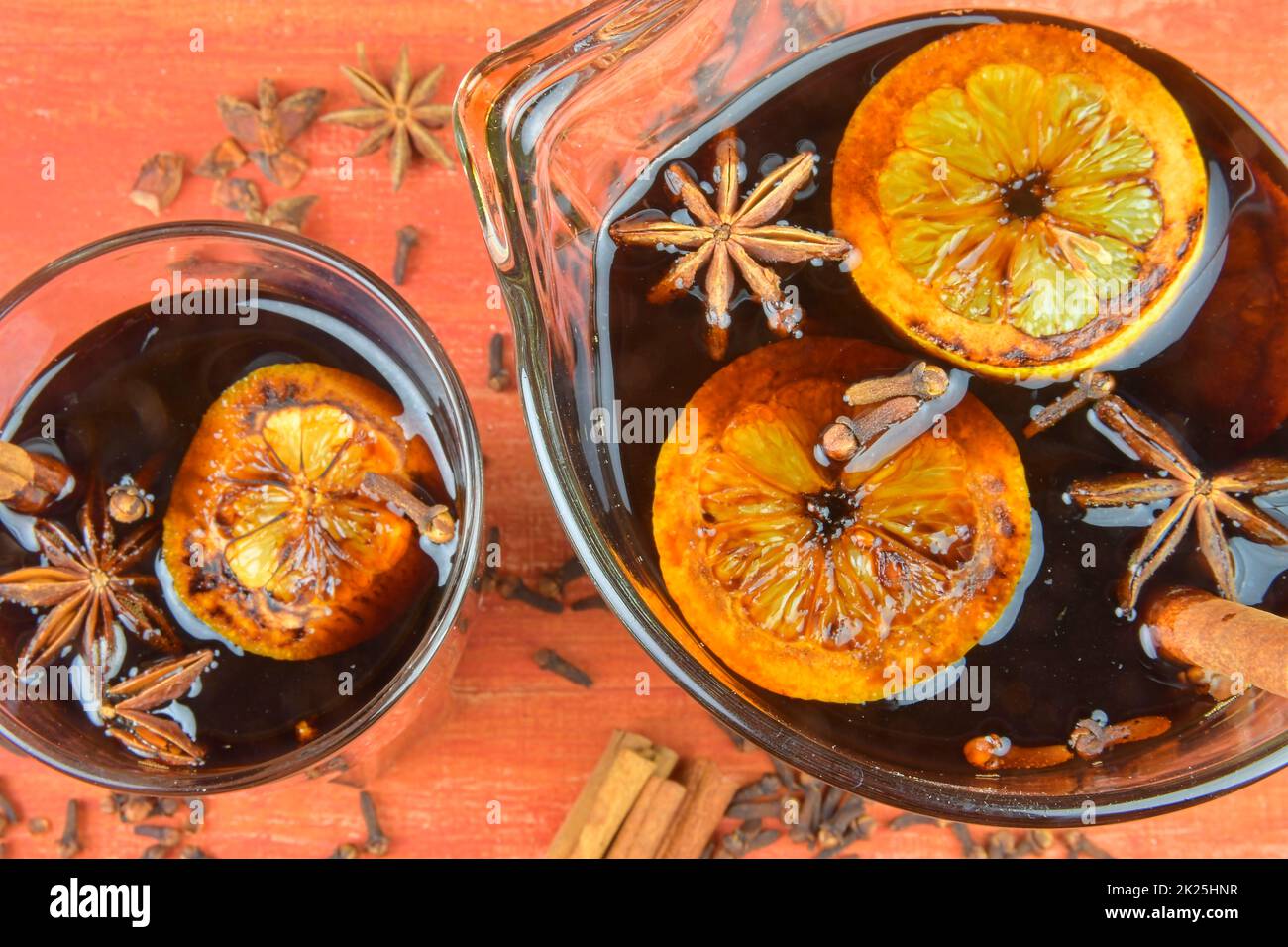 Christmas or New Year hot winter drink, spicy grog cocktail, sangria or mulled wine with tea, lemon, rum, cinnamon, anise star. Christmas mulled red wine in a glass on a wooden table. Close-up. POV - directly above Stock Photo