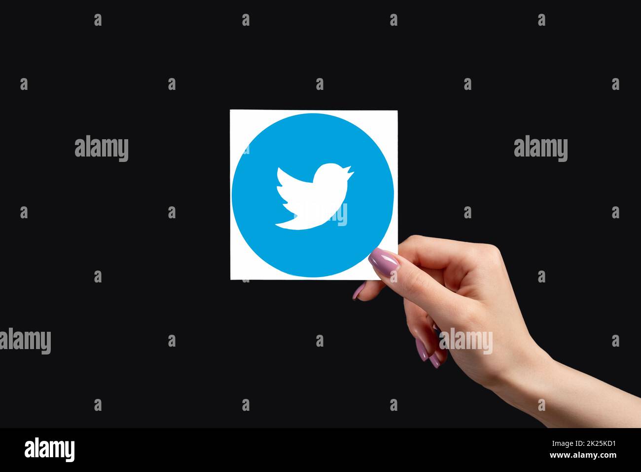 Kharkiv, Ukraine - June 05, 2020: Twitter logo. Global communication. Social media. Female hand holding microblogging app icon isolated on black copy Stock Photo
