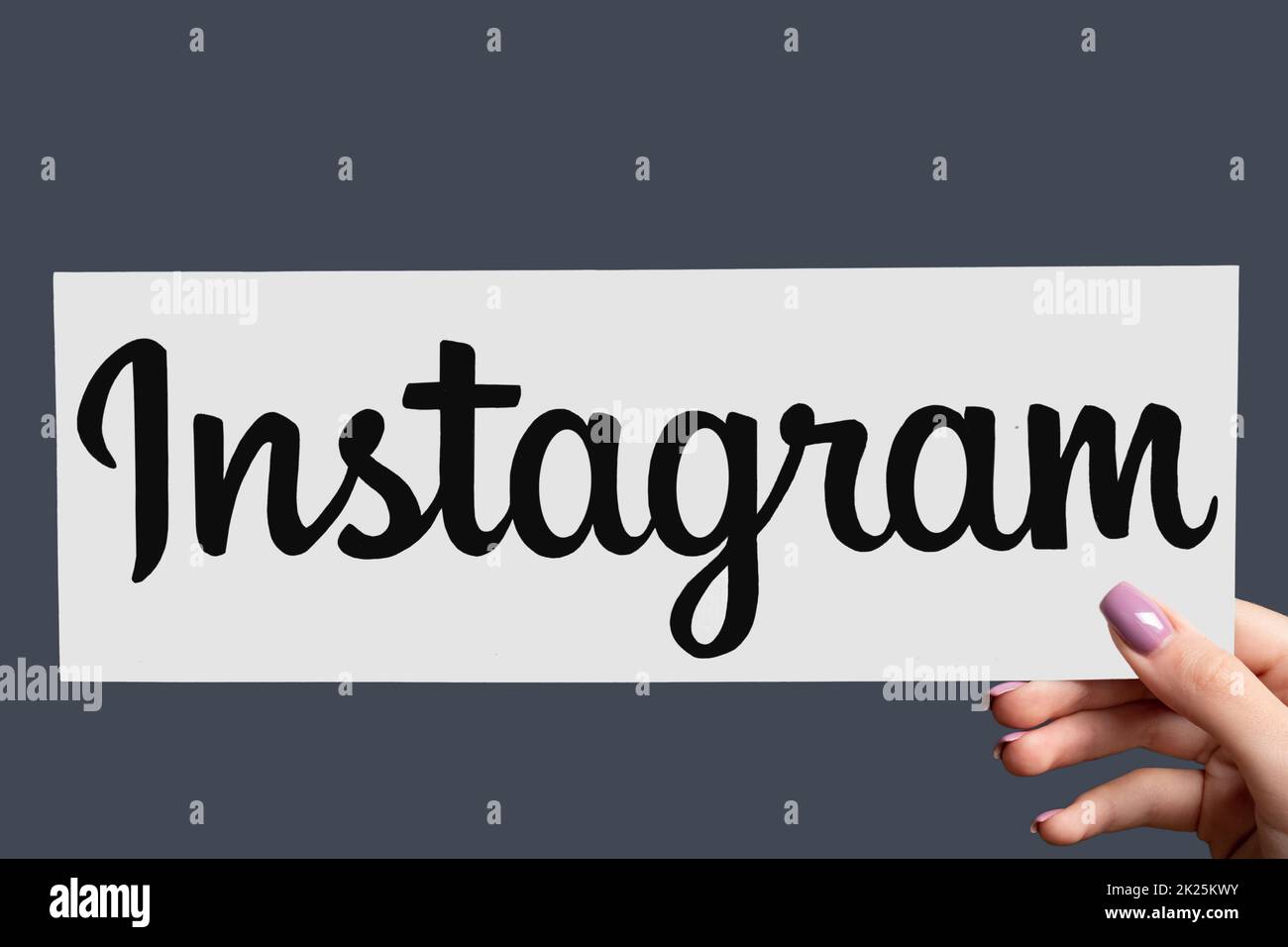 Kharkiv, Ukraine - June 05, 2020: Instagram sign. Social media. Online promotion. Follow network. Female hand showing mobile app icon isolated on purp Stock Photo