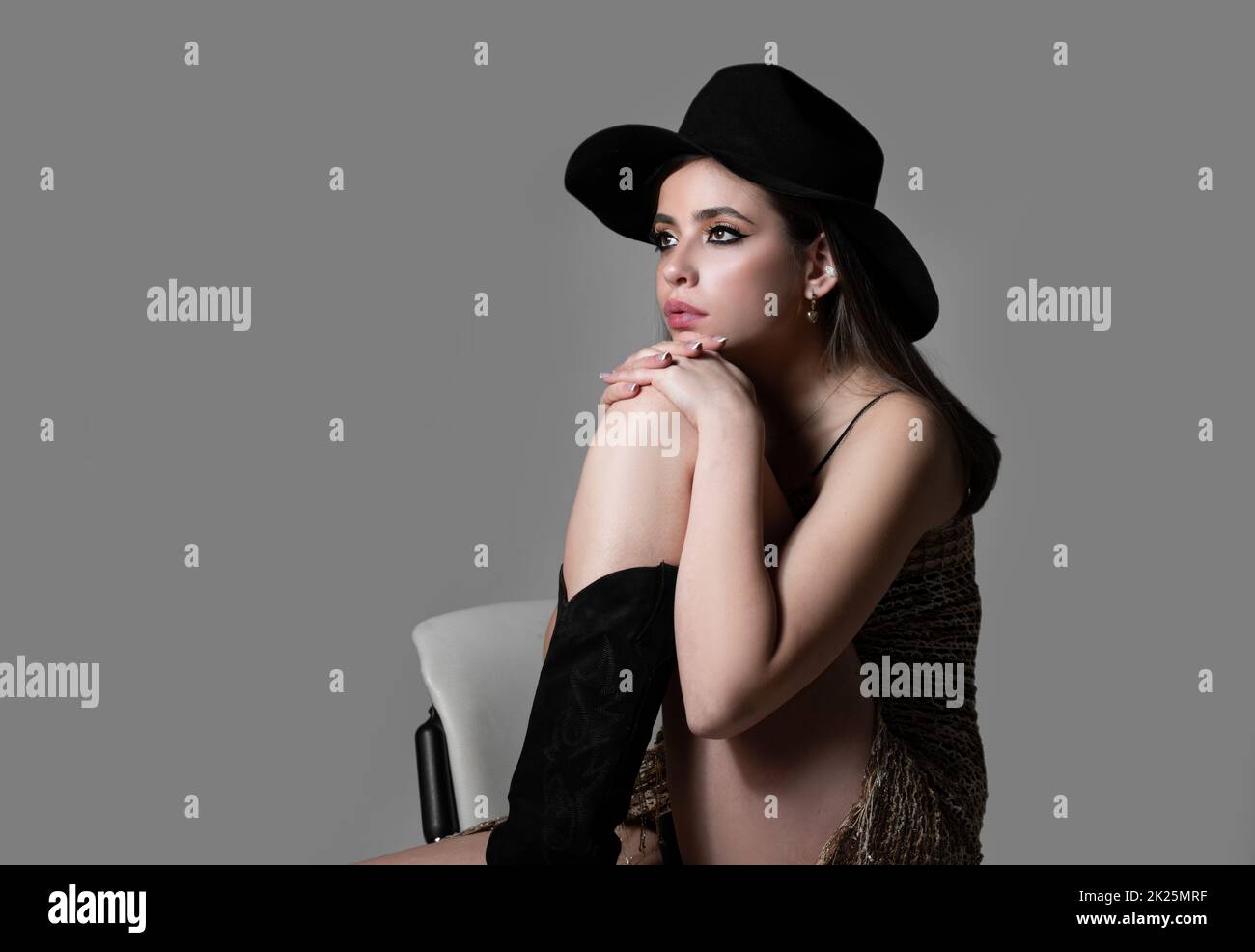 Fashion model in hat. Beautiful stylish girl in fashion dress posing isolated on studio background. Beautiful woman wearing vogue clothes. Fashion Stock Photo
