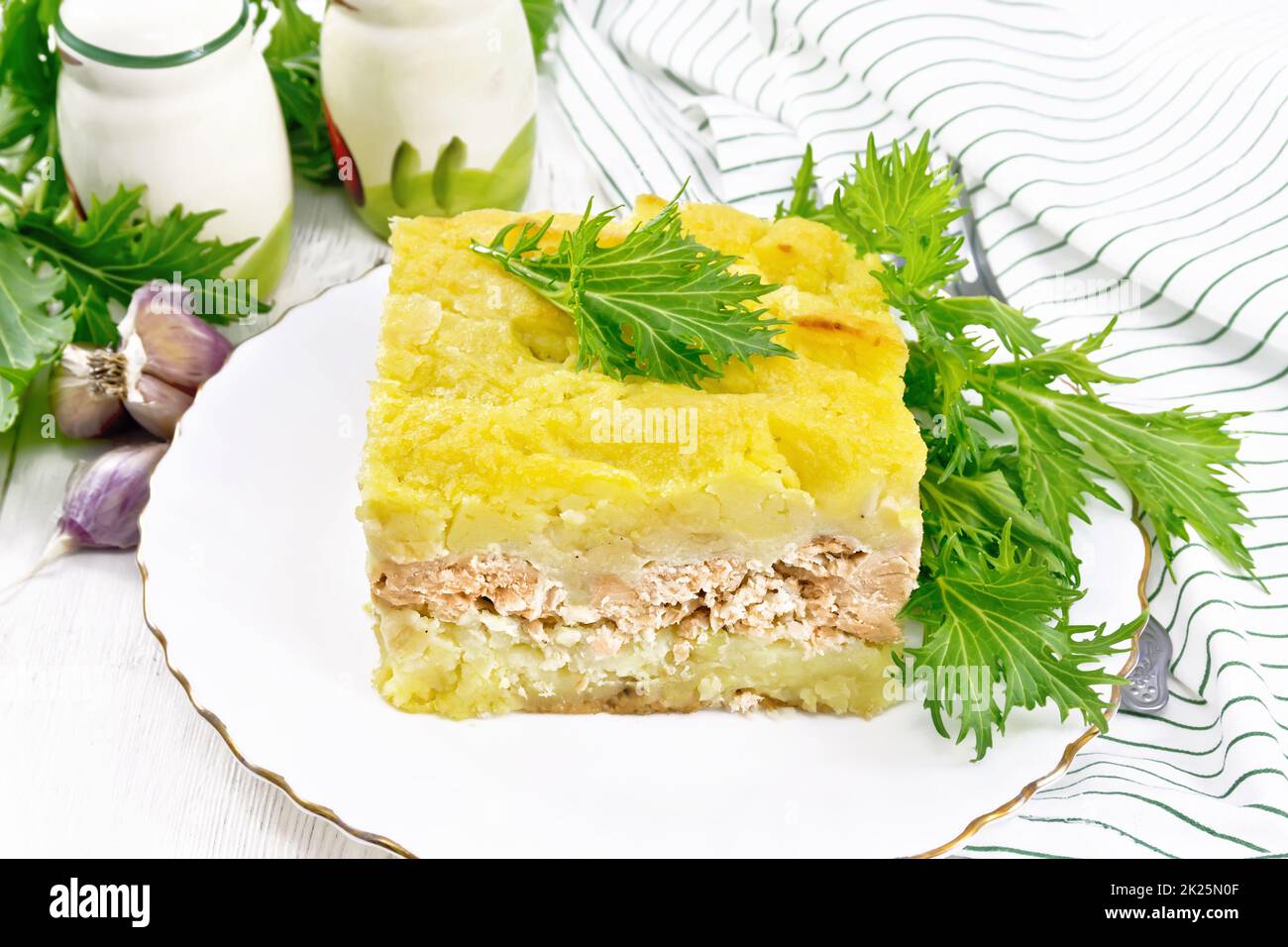 Casserole with potatoes and fish in plate on board Stock Photo