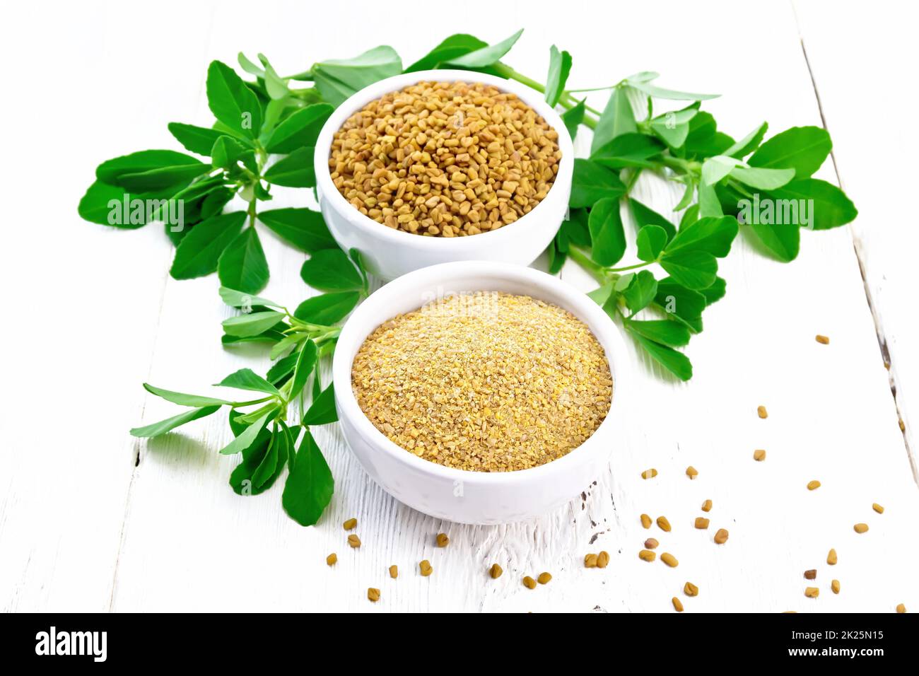 Fenugreek in two bowls with leaves on light board Stock Photo