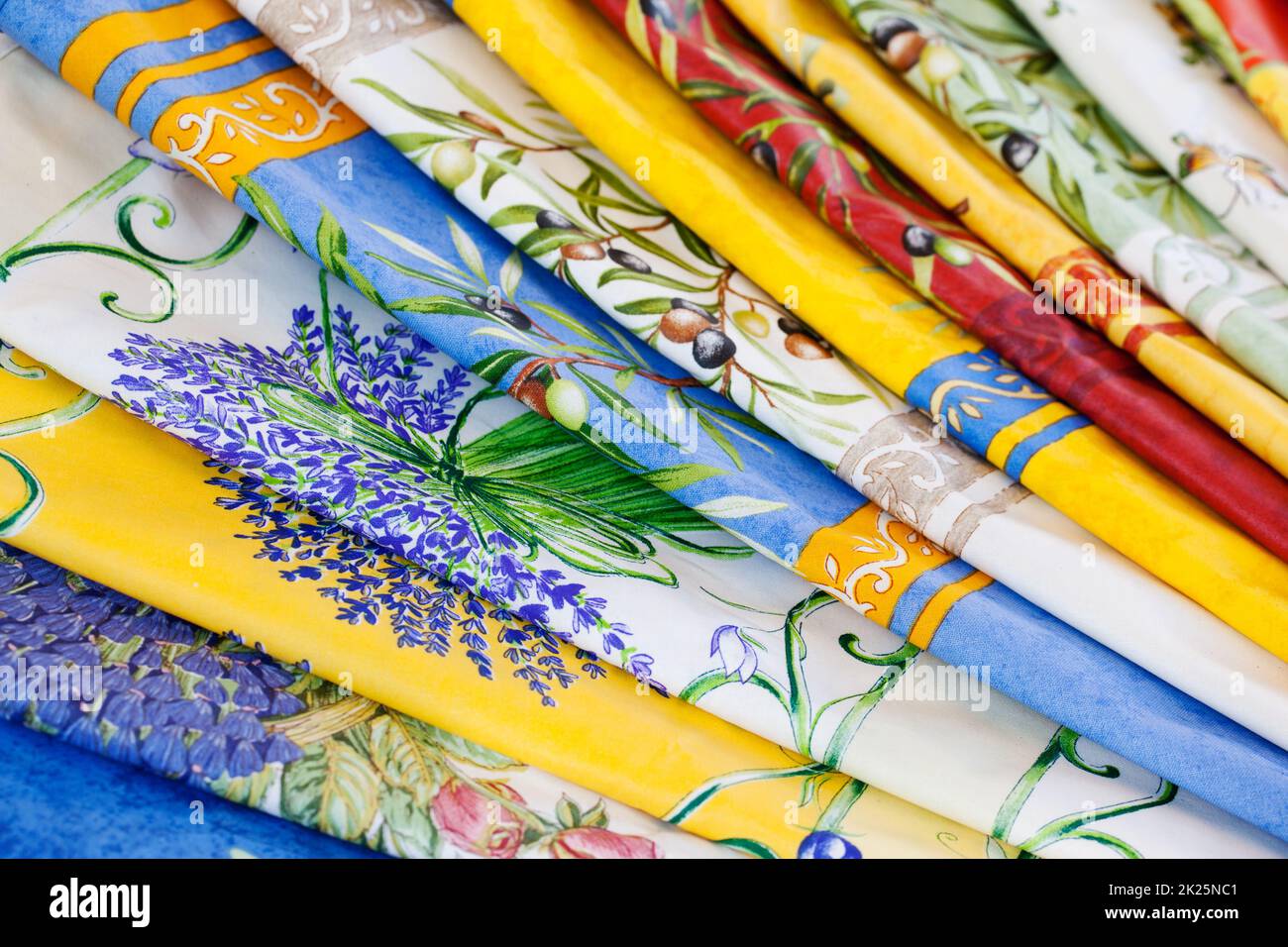 a stack of colorful tablecloths at a weekly market in Provence, France Stock Photo