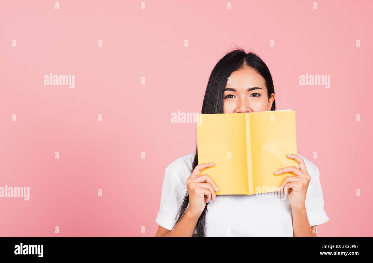 woman teen smile covering her face with yellow book Stock Photo Alamy