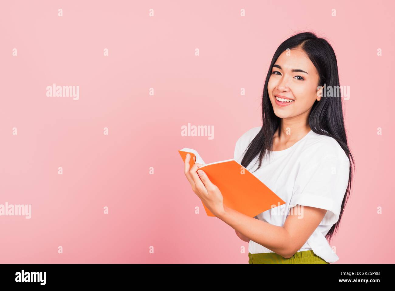 woman confident smiling standing holding orange book open Stock Photo