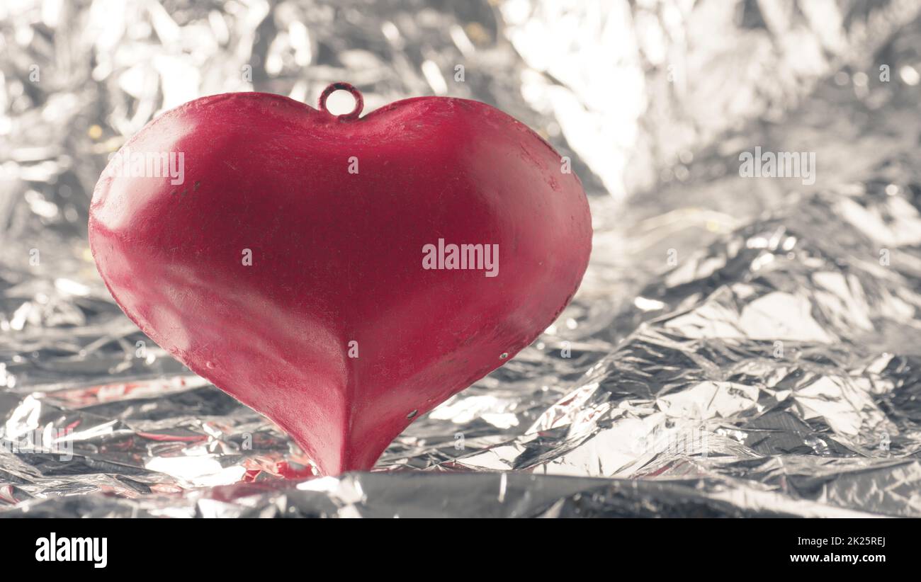 Red metal heartshape on a shiny silver background with space for text Stock Photo