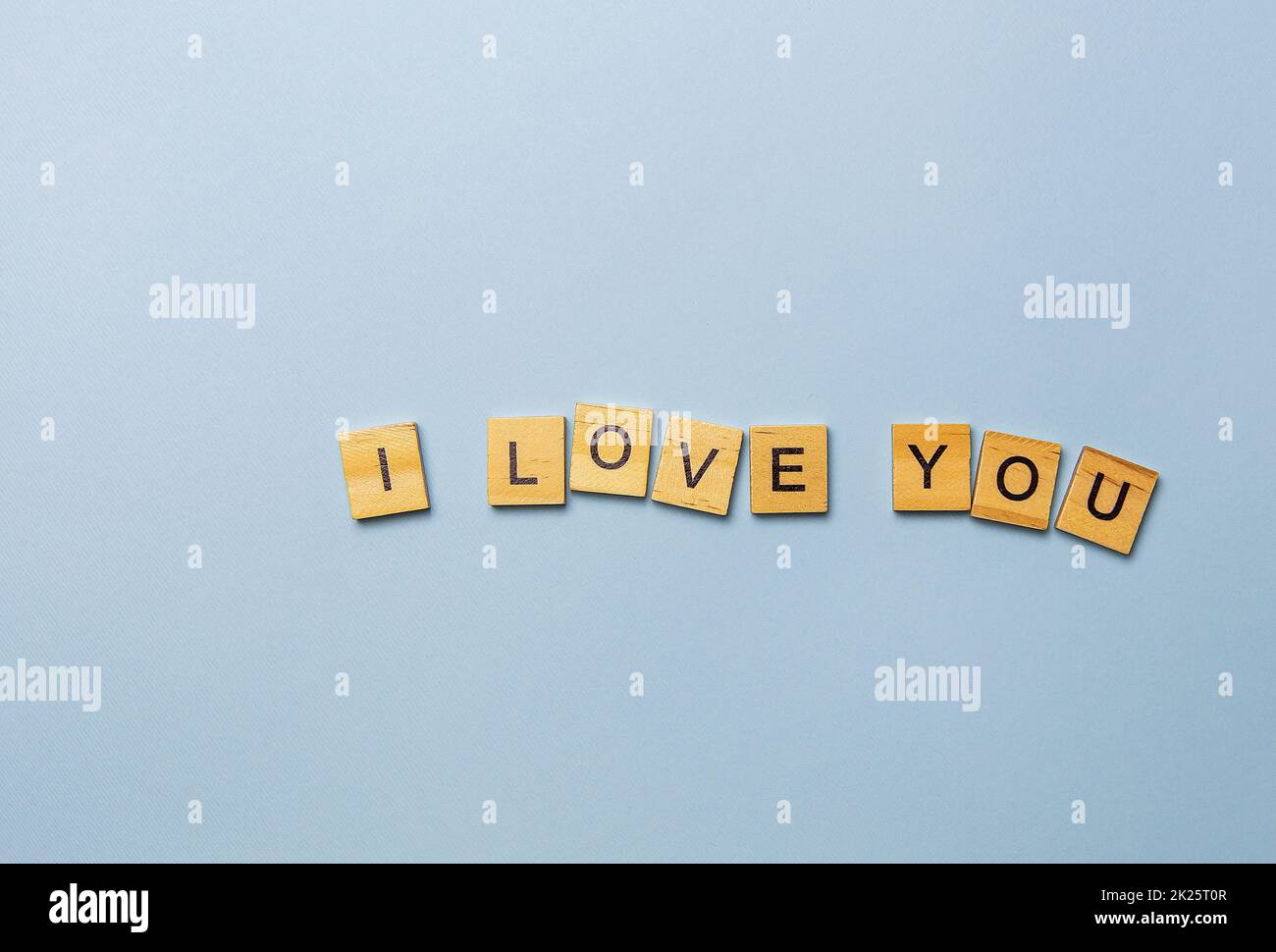 Inscription I love you in wooden letters on a blue background. Ready postcard, banner, place for an inscription. Stock Photo