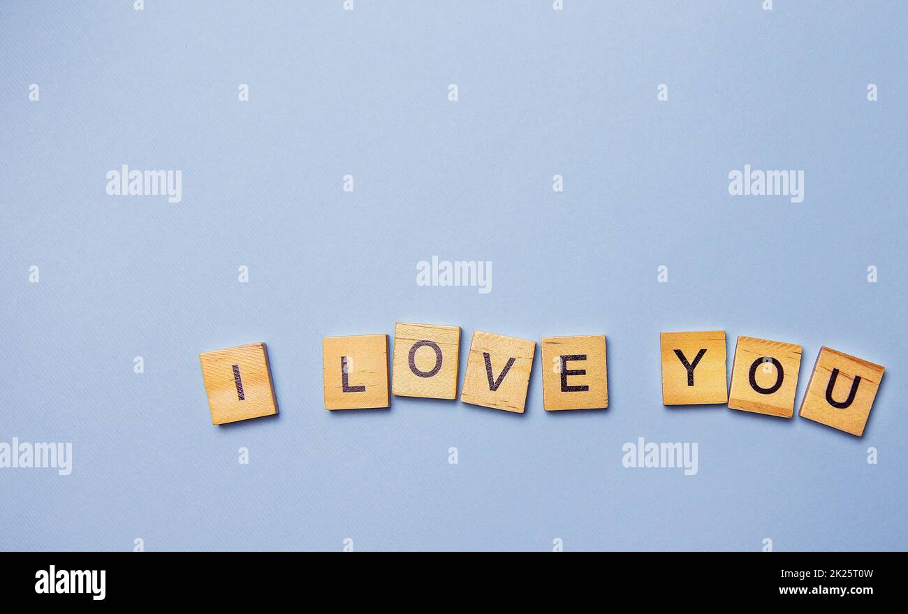 Inscription I love you in wooden letters on a blue background. Ready postcard, banner, place for an inscription. Stock Photo