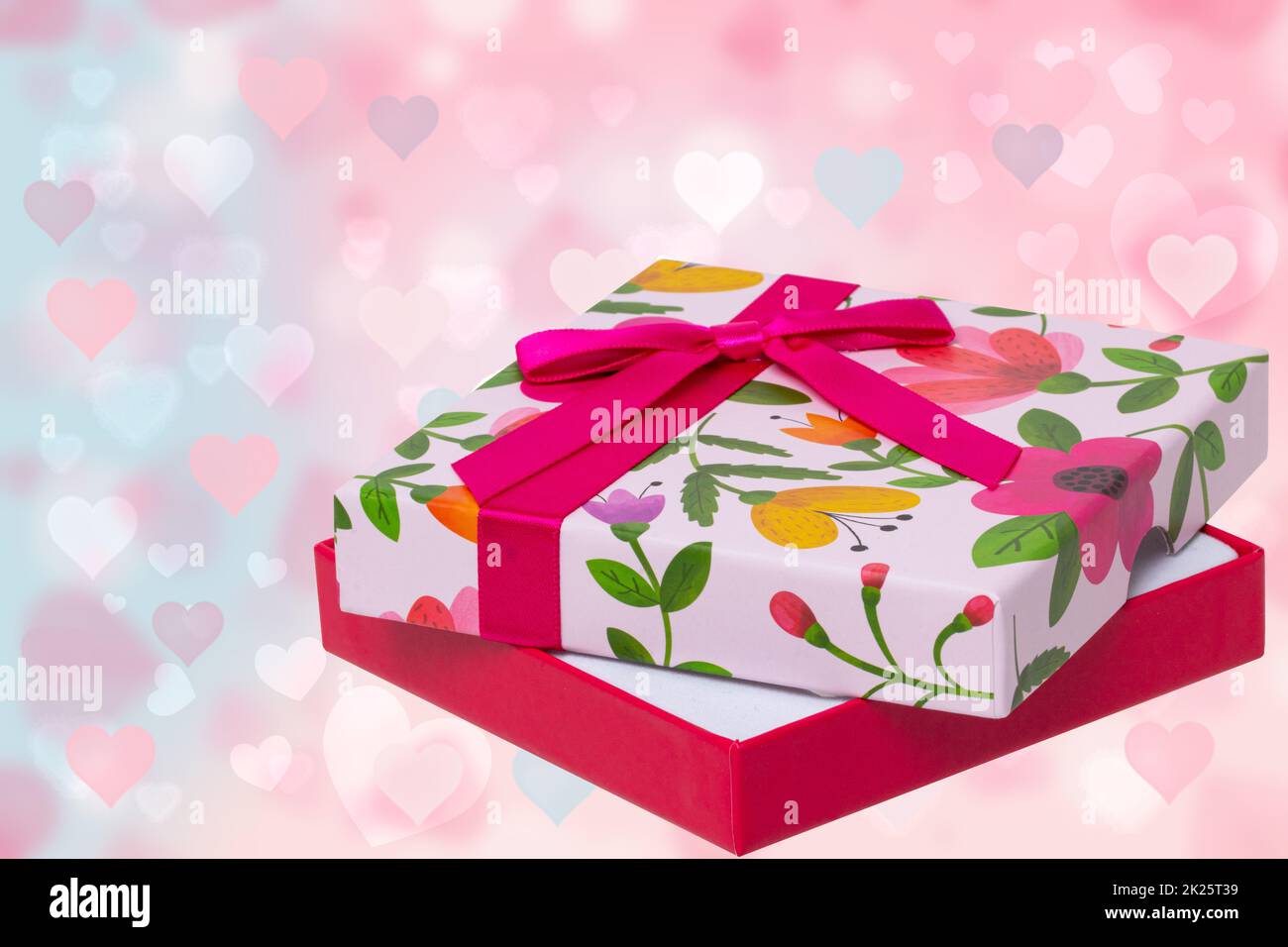 Happy Valentine or Mothers Day card template. Beautiful colorful present box over abstract light pink blue pastel background with hearts. Space fort ext design. Stock Photo