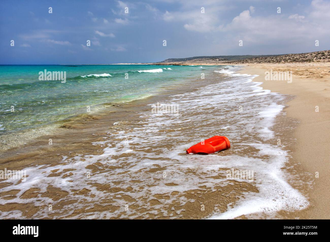 Bright red plastic oil (or washing liquid) container on beautiful unspoiled beach. Ocean plastics littering concept. Karpazz, Northern Cyprus. Stock Photo