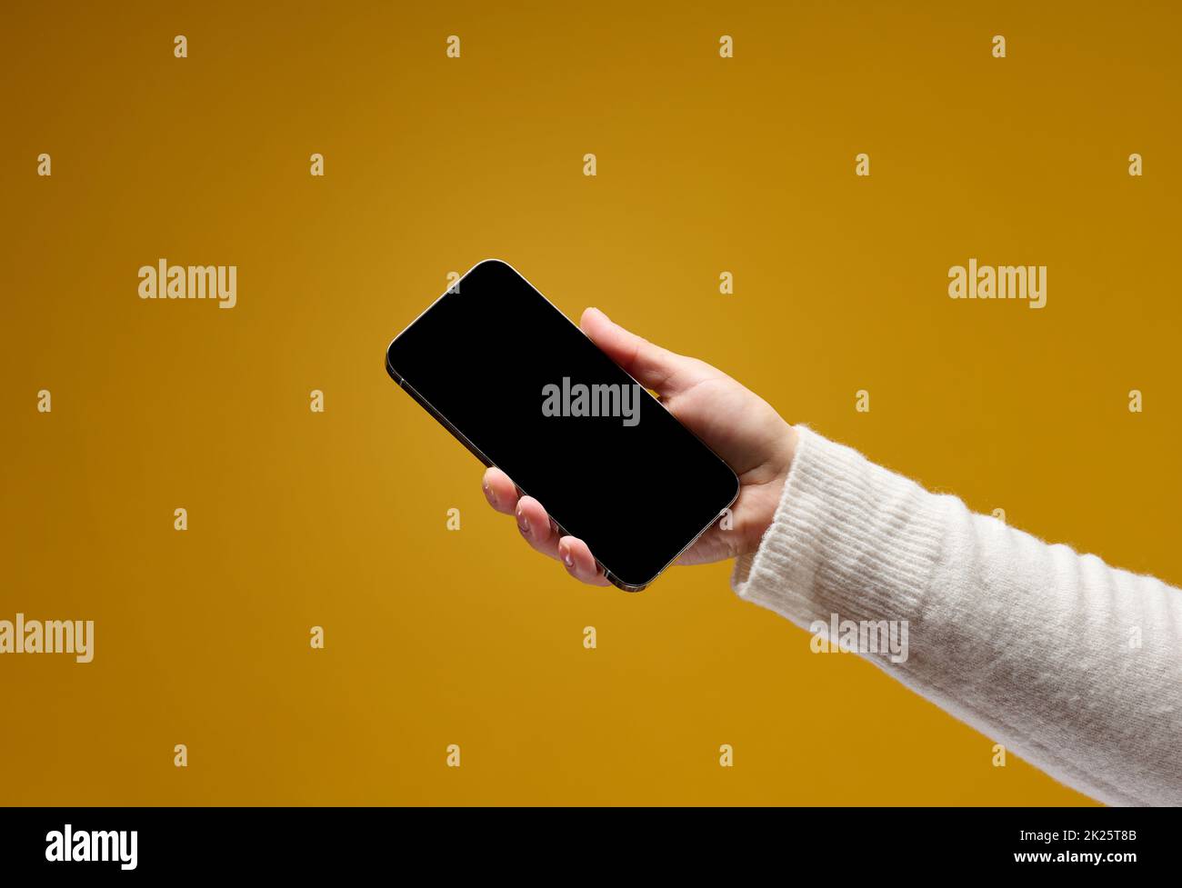 female hand holding smartphone with blank black screen on yellow ...