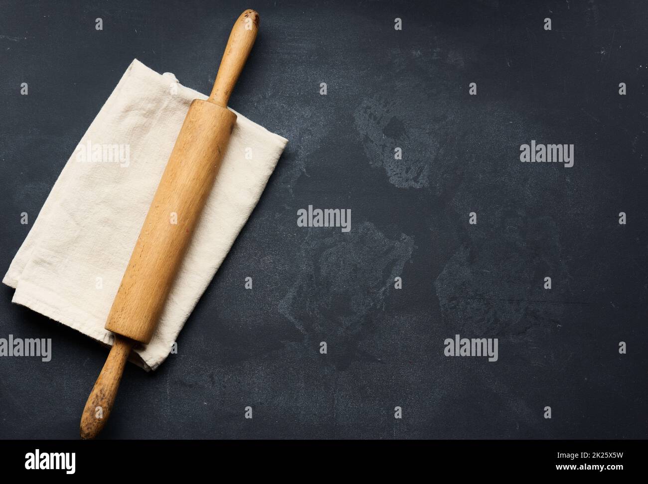 old wooden rolling pin for rolling dough on a black background, top