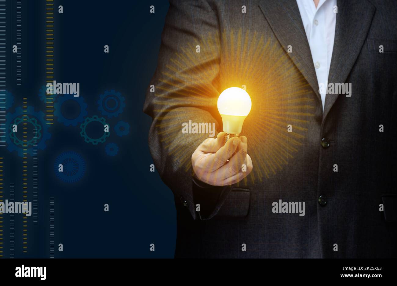 A businessman holds an electric lamp in his hand on a dark blue background. Concept of new ideas in business, innovation Stock Photo